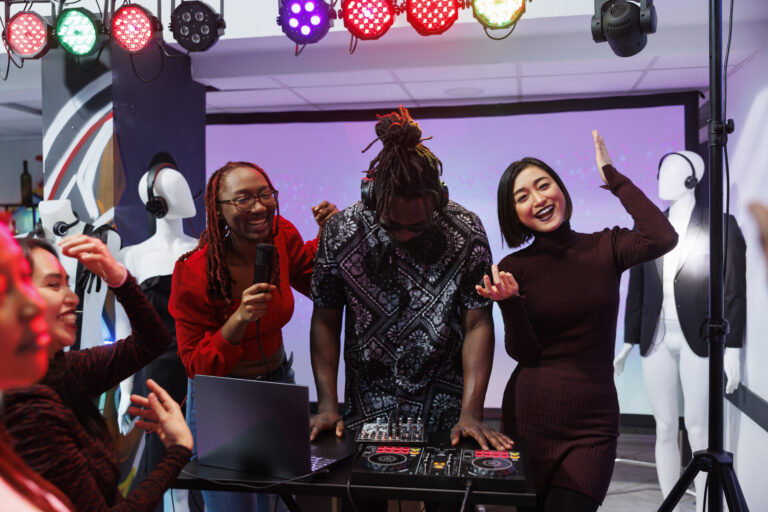 Happy smiling musicians laughing and performing on stage at nightclub party. Carefree energetic electronic music band singing and playing for clubbers at discotheque in club